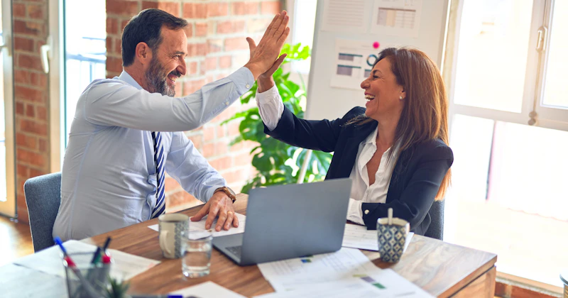 Business owner with a checklist reviewing web developer proposals, with multiple website mockups on the desk